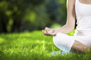 zen picture of half of a female figure practicing yoga in a backyard